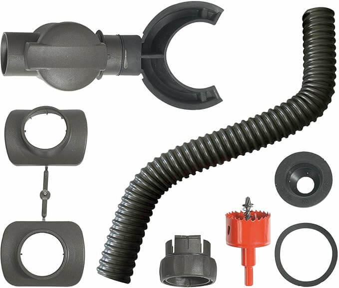 Eine Sammlung verschiedener schwarzer und roter Kunststoffteile für die Sanitärtechnik, darunter ein flexibler Wellschlauch, Armaturen, Anschlüsse, eine runde Klemme und ein roter Lochsägebohrer, die alle auf einem weißen Hintergrund angeordnet sind.